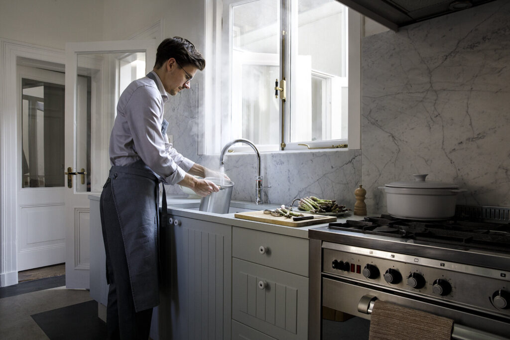 A picture of a man demonstrating Quooker's boiling water feature of their taps.